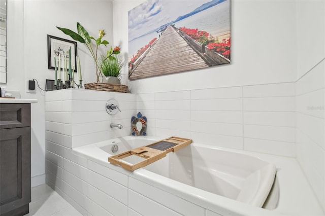 bathroom with tile patterned flooring, vanity, and a relaxing tiled tub