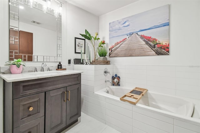 bathroom with vanity, tiled tub, and tile patterned flooring