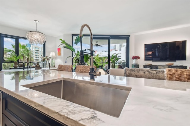 kitchen featuring hanging light fixtures, light stone countertops, sink, and a chandelier