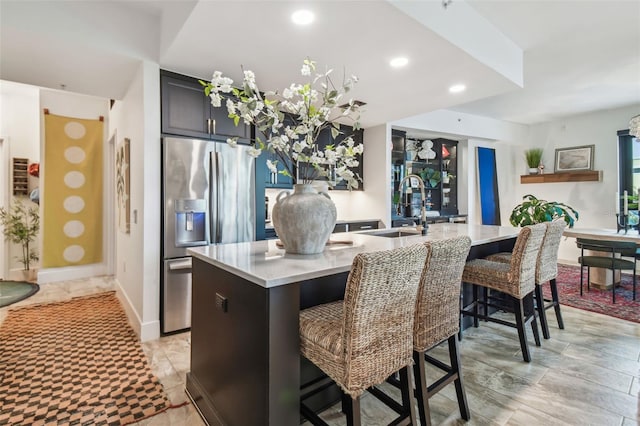 kitchen featuring a kitchen breakfast bar, sink, stainless steel fridge with ice dispenser, and an island with sink