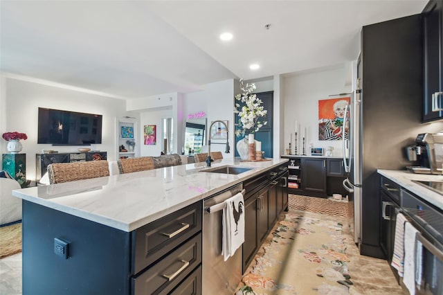 kitchen featuring sink, a breakfast bar area, light stone counters, a center island with sink, and stainless steel dishwasher