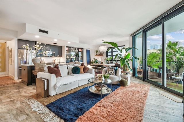 living room with an inviting chandelier, sink, and a wall of windows