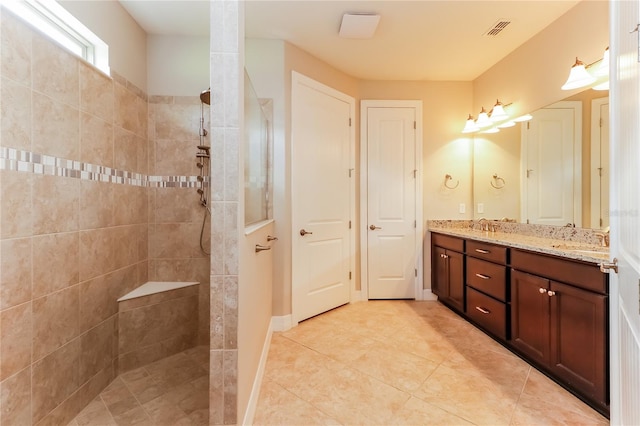 bathroom with tile patterned flooring, vanity, and tiled shower