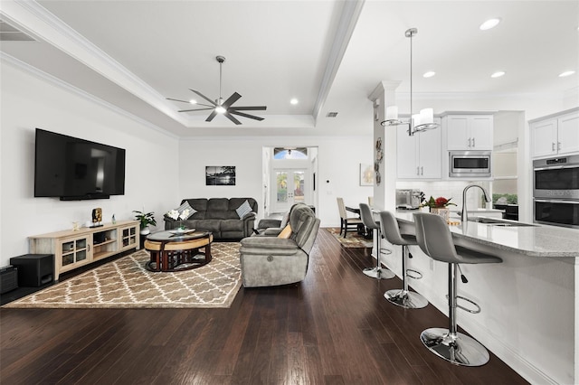 living room with crown molding, sink, ceiling fan, and dark wood-type flooring