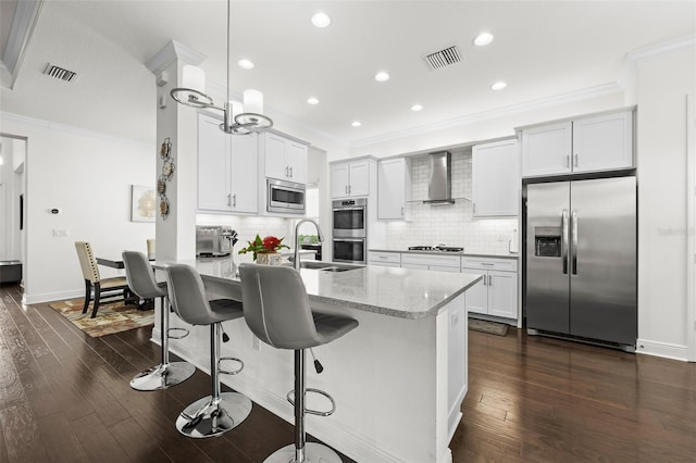 kitchen featuring hanging light fixtures, wall chimney exhaust hood, light stone counters, dark hardwood / wood-style flooring, and stainless steel appliances