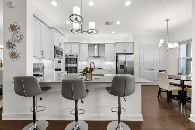 kitchen featuring crown molding, wall chimney exhaust hood, decorative light fixtures, dark hardwood / wood-style flooring, and stainless steel appliances