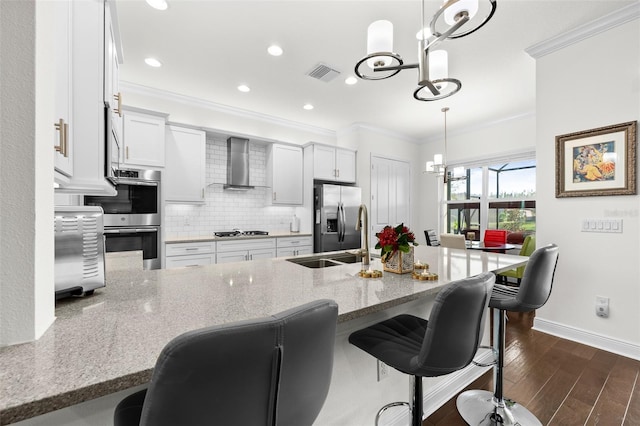 kitchen featuring hanging light fixtures, dark wood-type flooring, wall chimney range hood, and appliances with stainless steel finishes