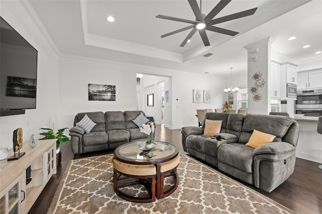 living room with a raised ceiling, ceiling fan with notable chandelier, dark hardwood / wood-style floors, and ornamental molding