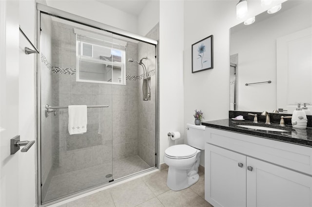 bathroom featuring tile patterned floors, a shower with door, vanity, and toilet