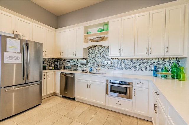 kitchen featuring white cabinets, sink, light tile patterned floors, tasteful backsplash, and stainless steel appliances