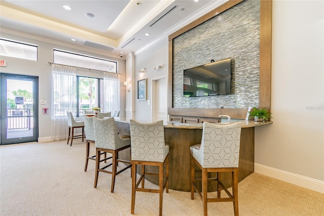 bar with a raised ceiling and light colored carpet