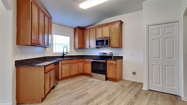 kitchen with sink, lofted ceiling, stainless steel appliances, and light hardwood / wood-style flooring