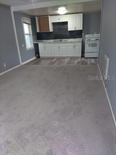 kitchen with backsplash, white cabinetry, carpet, and white electric range oven