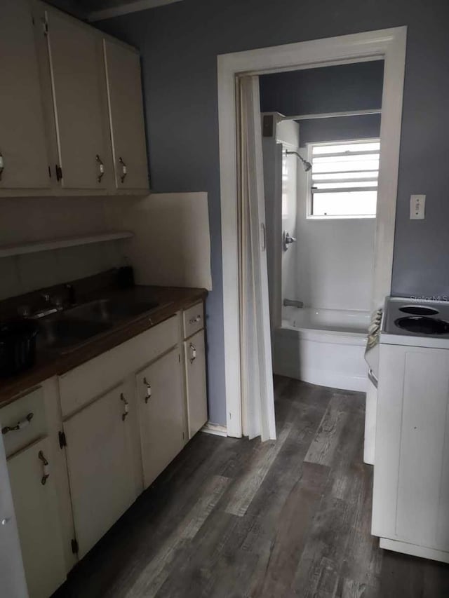 kitchen with electric range, sink, white cabinets, and dark hardwood / wood-style floors