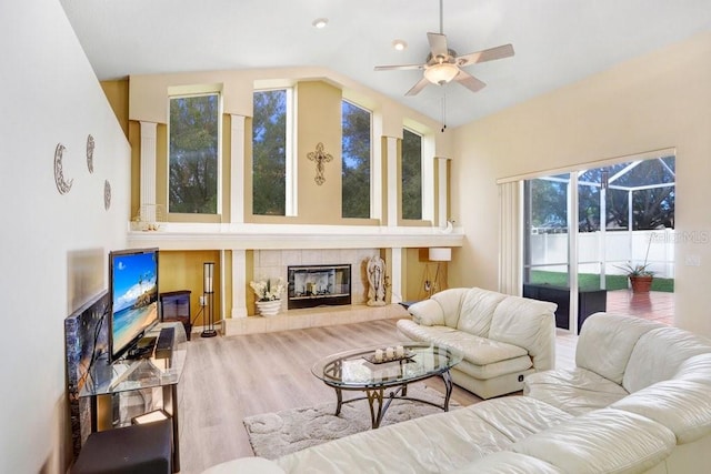 living room with a tile fireplace, ceiling fan, vaulted ceiling, and hardwood / wood-style flooring