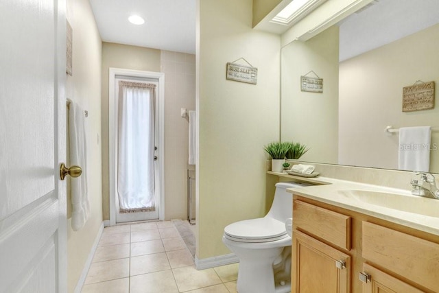 bathroom with toilet, vanity, a skylight, and tile patterned floors