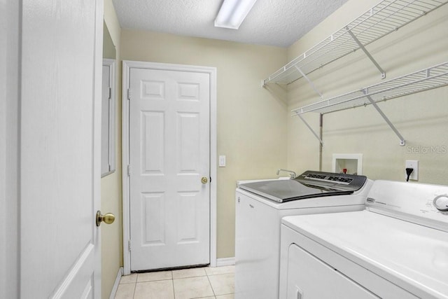 clothes washing area featuring washer and dryer, light tile patterned floors, and a textured ceiling