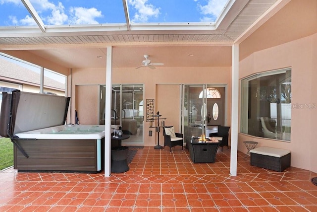 view of patio featuring glass enclosure, ceiling fan, and a hot tub