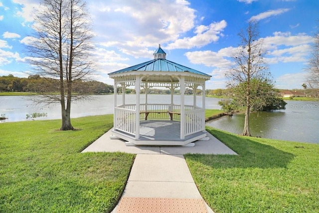 view of dock with a gazebo, a lawn, and a water view