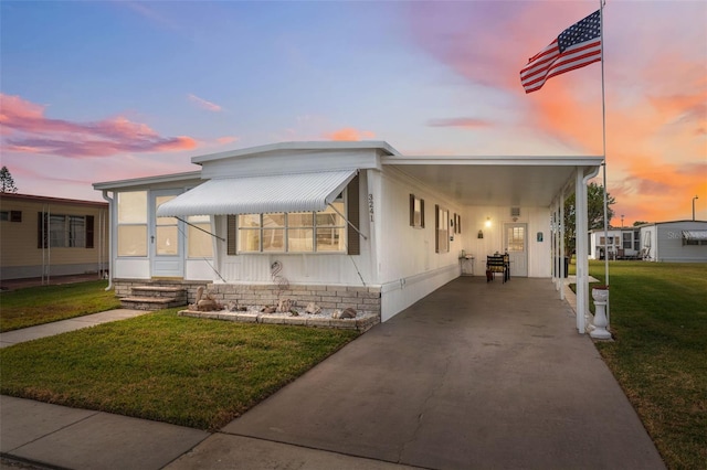 manufactured / mobile home with a yard and a carport