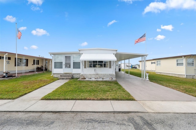 manufactured / mobile home featuring a carport, a sunroom, and a front yard