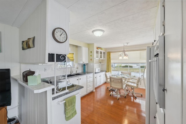 kitchen with white cabinets, wood-type flooring, hanging light fixtures, and sink