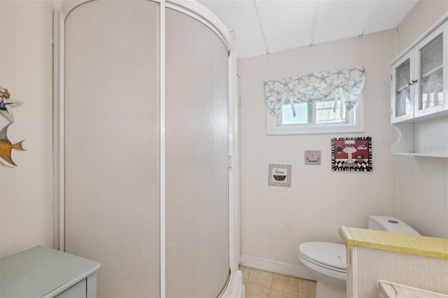 bathroom with tile patterned flooring, toilet, and a shower with shower door