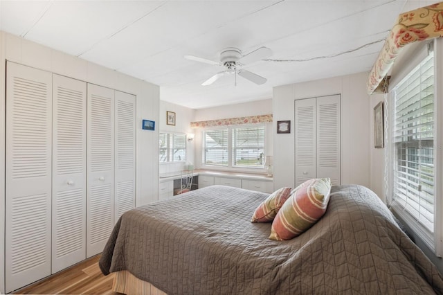 bedroom with ceiling fan, light hardwood / wood-style floors, and multiple closets