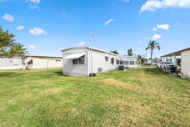 rear view of property featuring a lawn and central AC unit