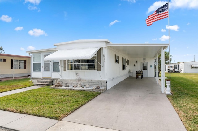 manufactured / mobile home featuring a carport, a sunroom, and a front yard