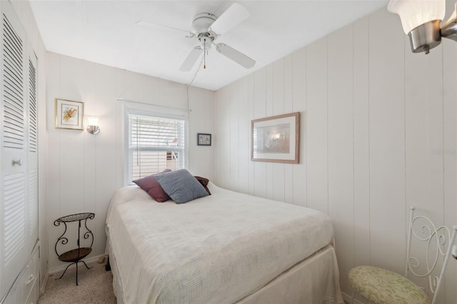 carpeted bedroom with ceiling fan, a closet, and wooden walls