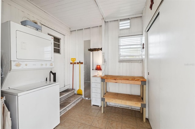 laundry room featuring wood ceiling, wood walls, light tile patterned floors, and stacked washing maching and dryer