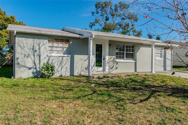 ranch-style house with stucco siding, a front lawn, and fence