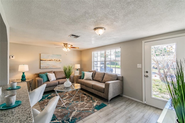 living room featuring plenty of natural light, a textured ceiling, and light wood-type flooring