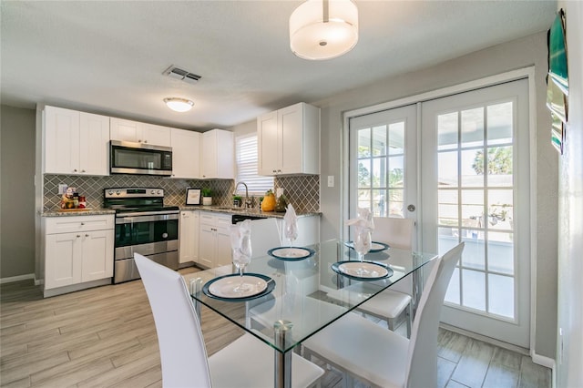 kitchen with sink, light wood-type flooring, white cabinetry, and stainless steel appliances