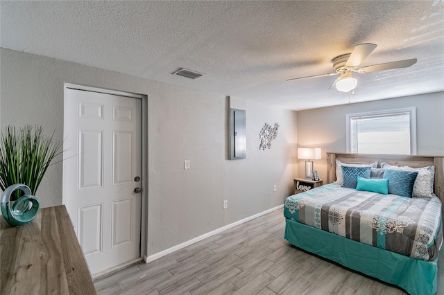 bedroom featuring a textured ceiling, light hardwood / wood-style floors, and ceiling fan