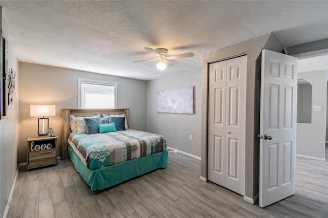 bedroom featuring ceiling fan, a textured ceiling, and light hardwood / wood-style flooring