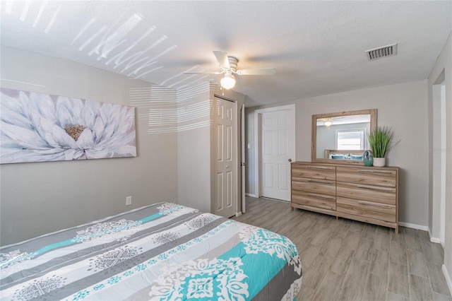 bedroom with a textured ceiling, a closet, light hardwood / wood-style floors, and ceiling fan