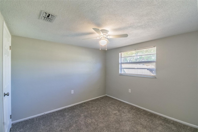 spare room with a textured ceiling and dark carpet