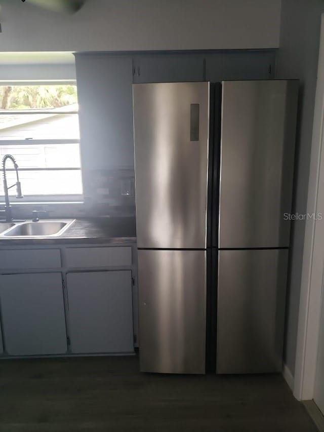 kitchen featuring stainless steel fridge, white cabinetry, and sink