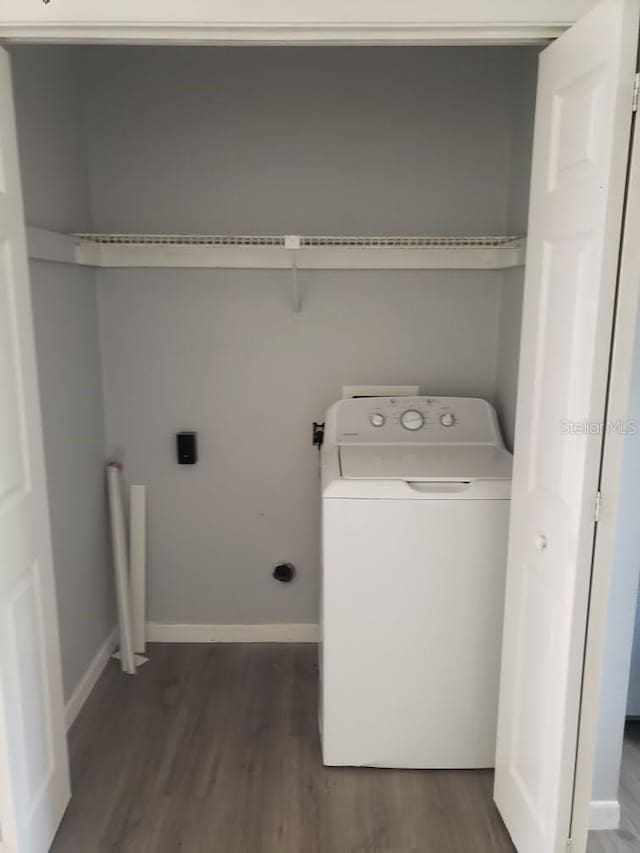 clothes washing area with washer / dryer and dark wood-type flooring