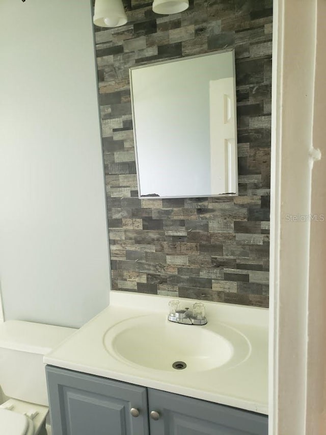 bathroom featuring vanity, toilet, and tasteful backsplash