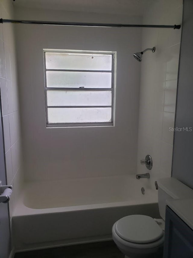 full bathroom featuring tiled shower / bath, toilet, and plenty of natural light