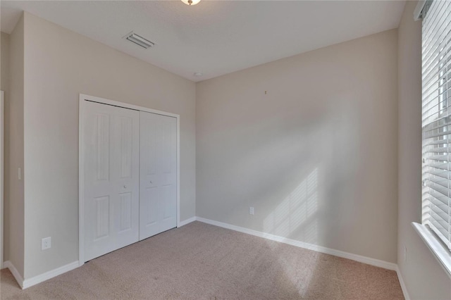 unfurnished bedroom featuring light colored carpet and a closet