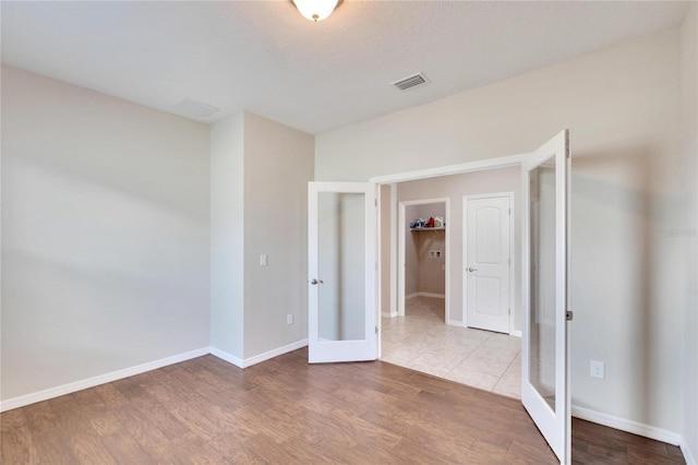 unfurnished bedroom with french doors, a textured ceiling, hardwood / wood-style flooring, and a closet