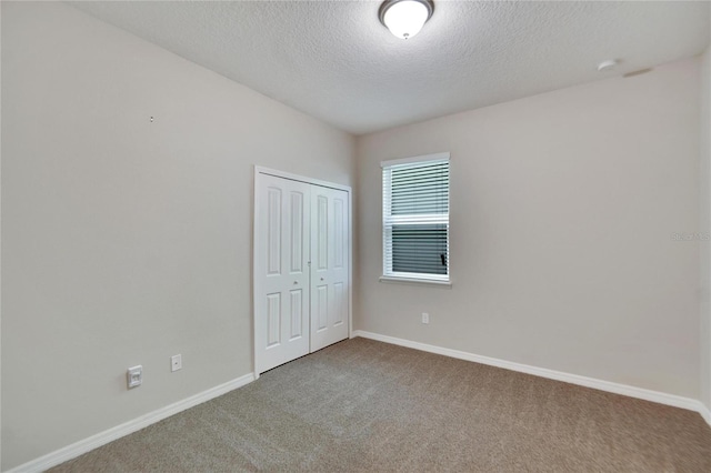 unfurnished room with carpet flooring and a textured ceiling