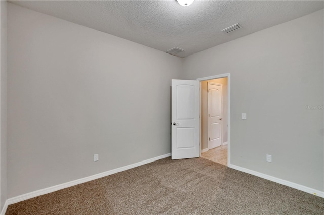 spare room featuring a textured ceiling and light colored carpet