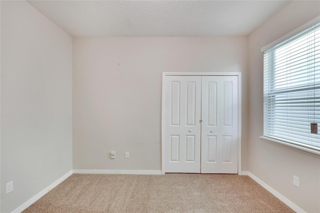 unfurnished bedroom featuring a closet, light colored carpet, and a textured ceiling