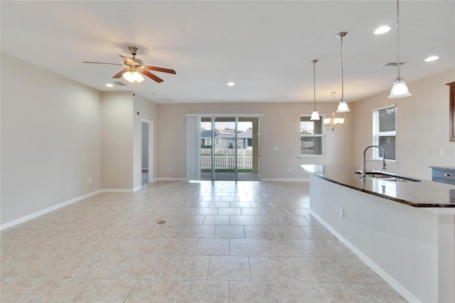 kitchen featuring sink, light tile patterned floors, pendant lighting, and ceiling fan with notable chandelier