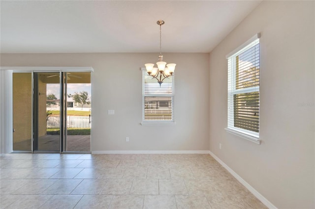 empty room with light tile patterned flooring and a chandelier